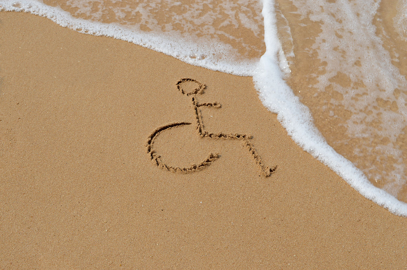 A wheelchair symbol drawn in sand near the shoreline as a wave approaches accessibility audit website accessibility audit web accessibility audit